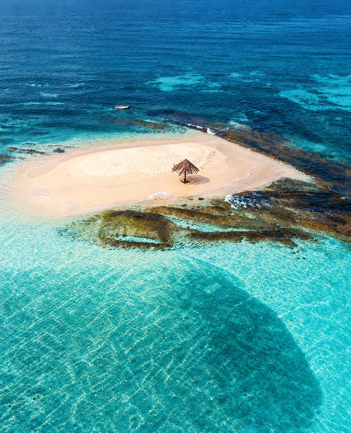 A sandbar with a single sunshade in turquoise water